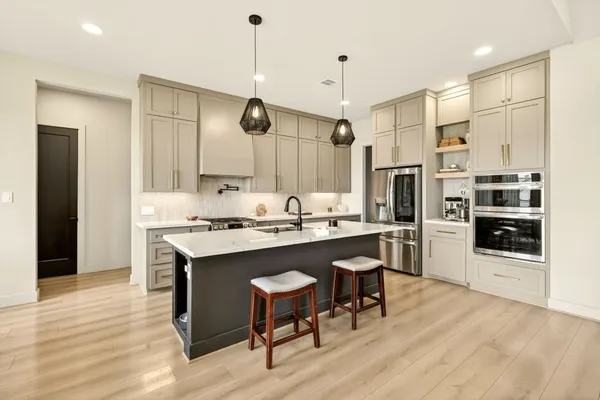a kitchen with stainless steel appliances granite countertop a sink a stove a refrigerator and island with wooden floor