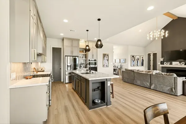 a kitchen with stainless steel appliances kitchen island granite countertop a stove top oven a sink dishwasher a dining table and chairs with wooden floor