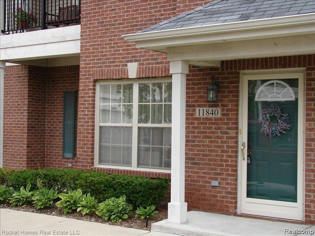 11840 Farmington Road, Unit 59 Livonia, MI 48150 - Photo 1 of 16 Brick exterior with a covered entry, featuring a dark green front door with an arched transom
