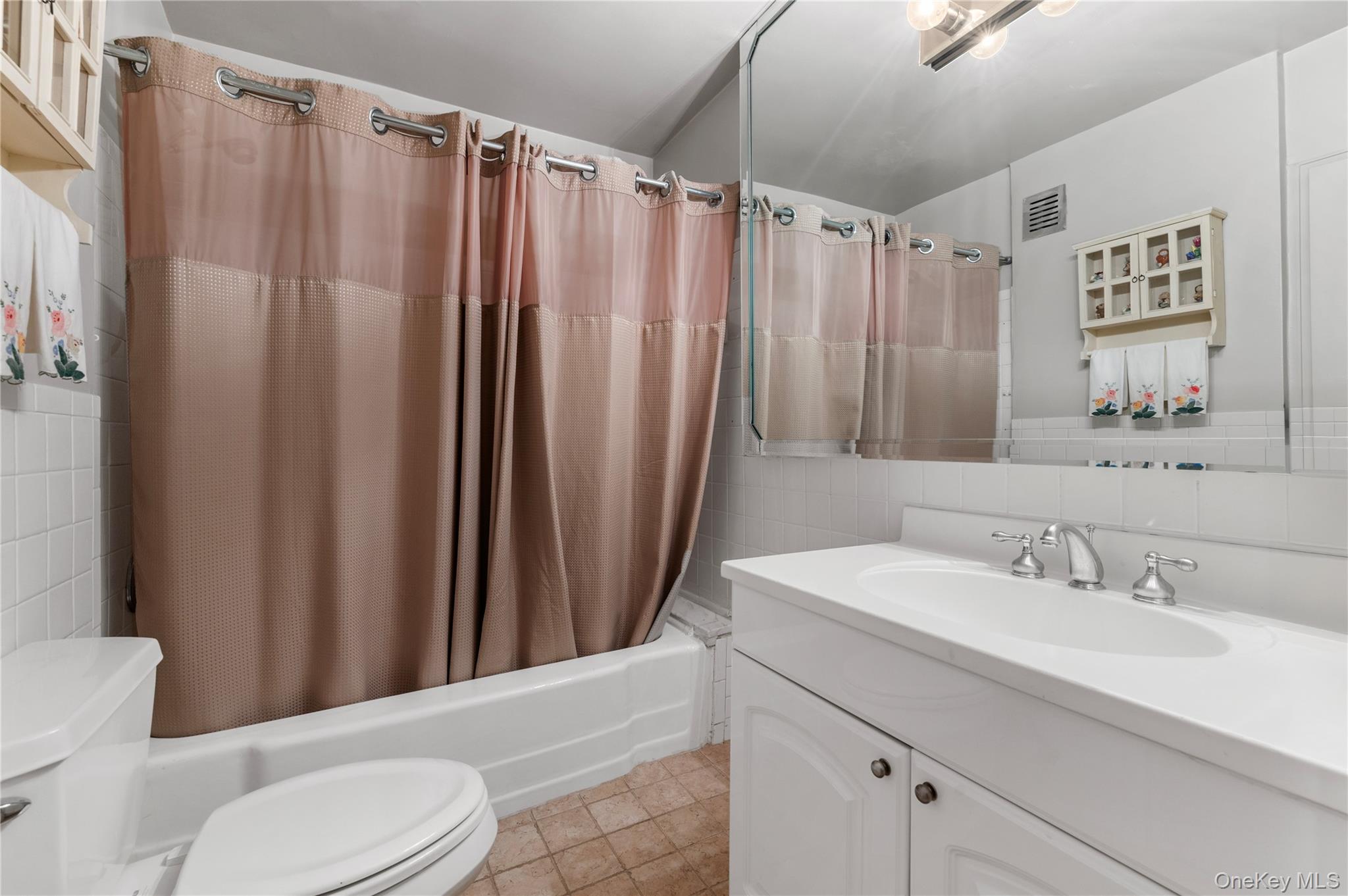 25 Chapel Place, Unit 2L Great Neck, NY 11021 - Photo 14 of 25 a bathroom with a sink a toilet a mirror and shower curtain