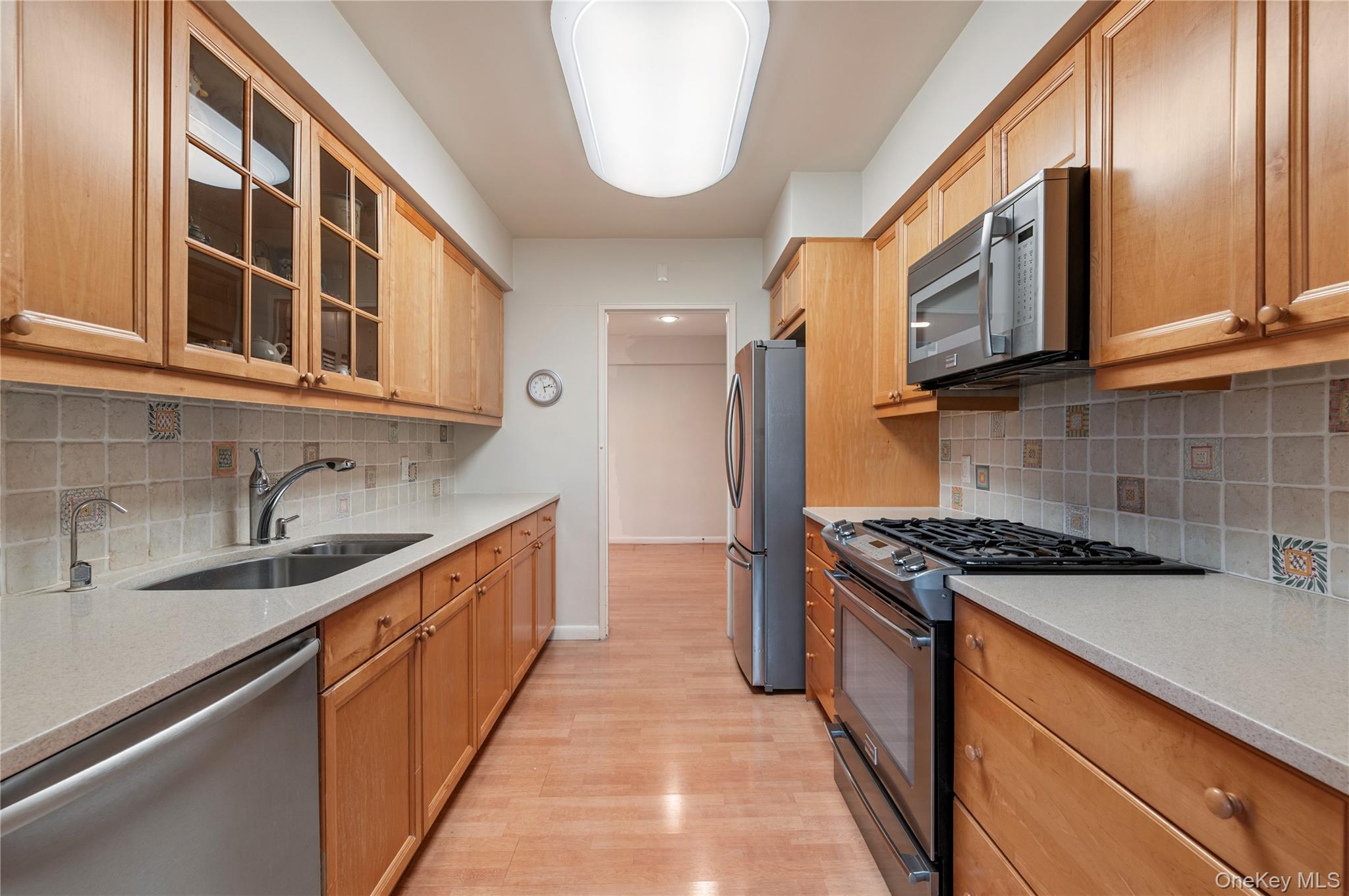 25 Chapel Place, Unit 2L Great Neck, NY 11021 - Photo 7 of 25 a kitchen with stainless steel appliances granite countertop a sink and a stove