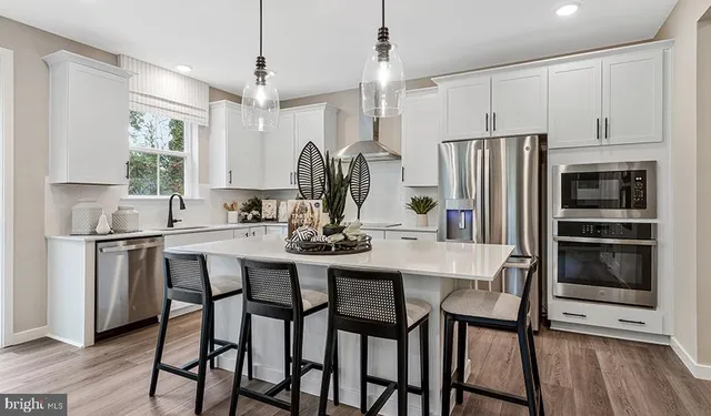 a kitchen with stainless steel appliances a refrigerator a stove a sink and chairs