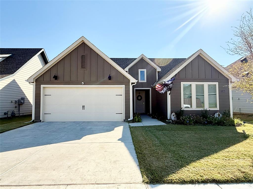 View of front of property with board and batten siding, a front lawn, driveway, a garage, and a shingled roof