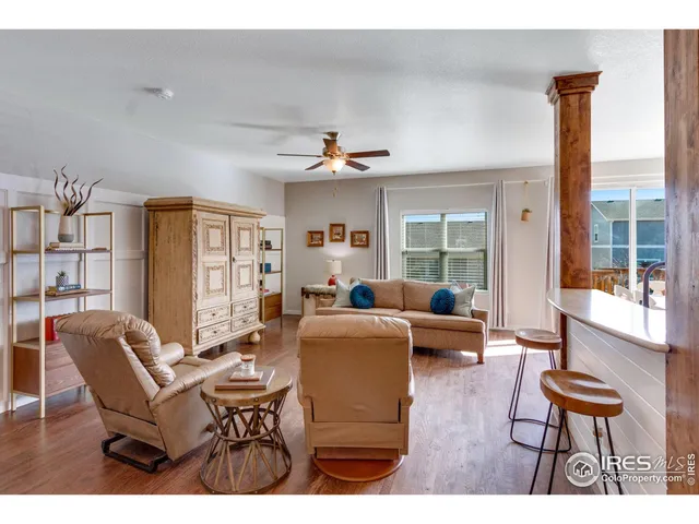 a living room with furniture a large window and wooden floor