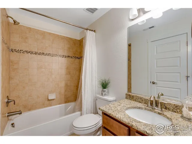 a bathroom with a granite countertop sink toilet a mirror and shower