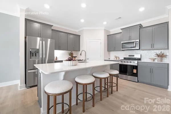 a kitchen with kitchen island granite countertop stainless steel appliances a sink a stove a table and chairs