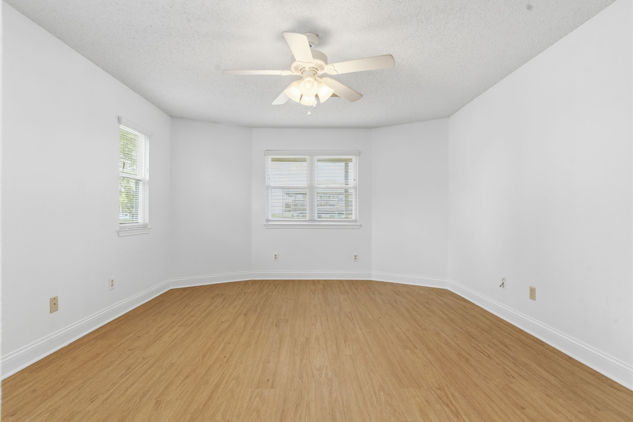 119 Sand Shoals Road Freeport, TX 77541 - Photo 23 of 34 Secondary bedroom — three window exposures for cross breezes, ceiling fan with light, soft white walls, and continuous LVP flooring throughout.