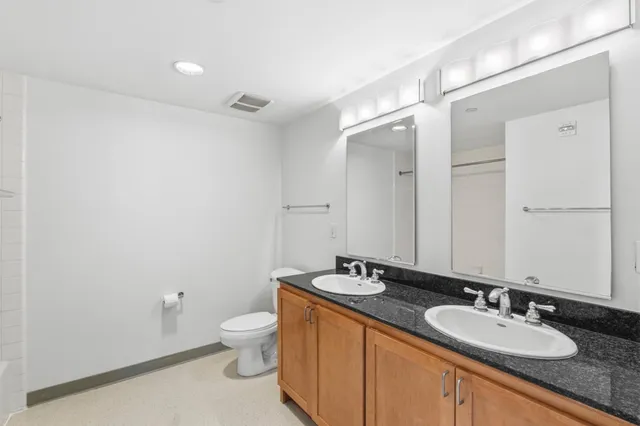 a bathroom with a granite countertop sink a toilet and a mirror