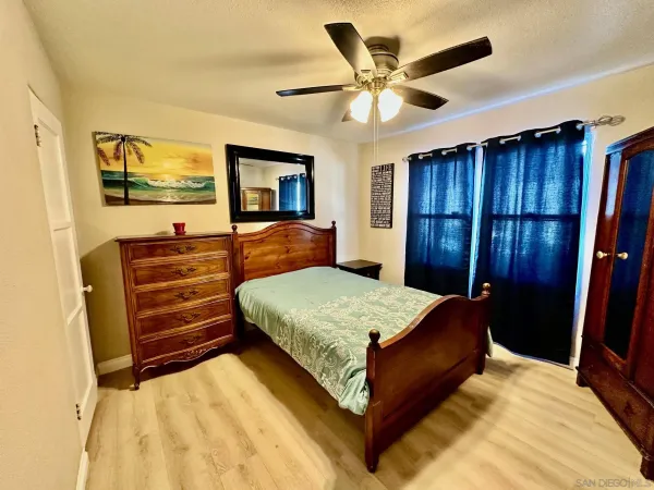 a bedroom with a bed a dresser and a chandelier