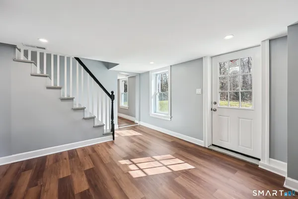 a view of an empty room with wooden floor and a window