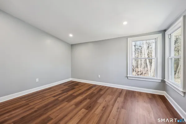 a view of empty room with wooden floor and fan