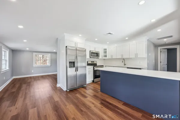 a large kitchen with stainless steel appliances kitchen island a large counter top and a refrigerator