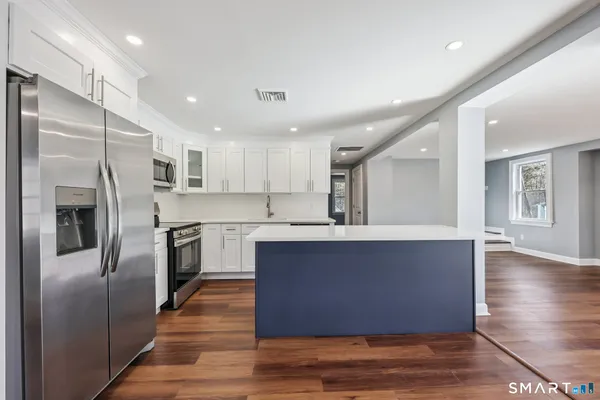 a large kitchen with stainless steel appliances granite countertop a refrigerator a sink a stove and oven