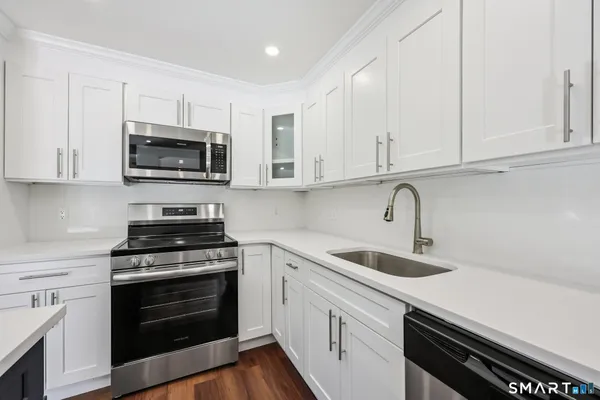 a kitchen with cabinets stainless steel appliances a sink and wooden floor