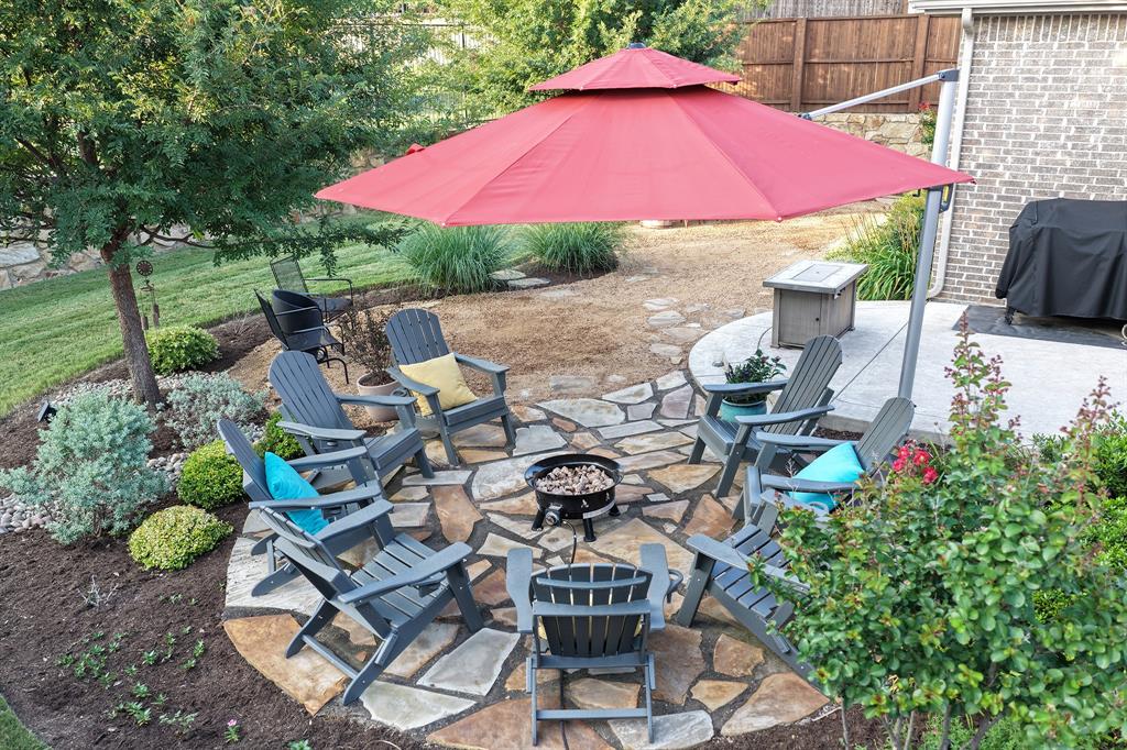 5213 Ravine Ridge Court Flower Mound, TX 76262 - Photo 31 of 40 Outdoor flagstone patio featuring a central fire pit area, surrounded by lush landscaping and mature trees.