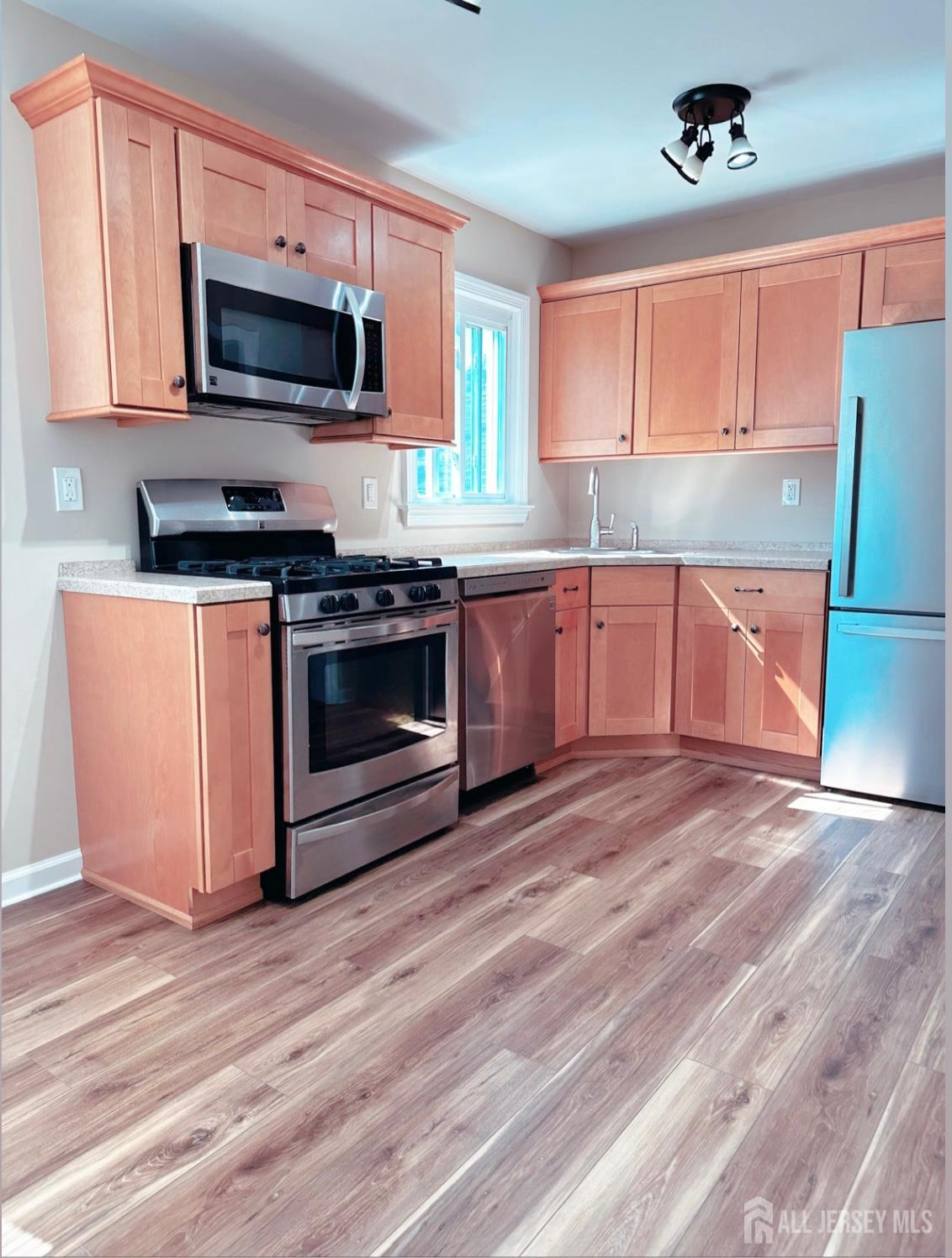 a kitchen with granite countertop a stove top oven a sink dishwasher and a refrigerator with wooden floor