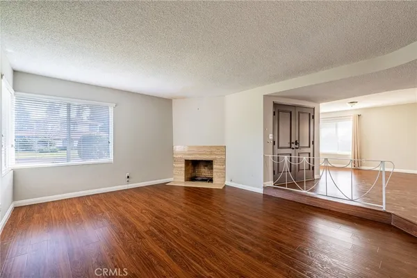 an empty room with wooden floor fireplace and windows