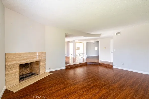 a view of an empty room with wooden floor fireplace and a window