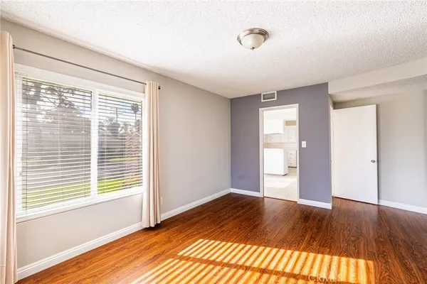 a view of an empty room with window and wooden floor