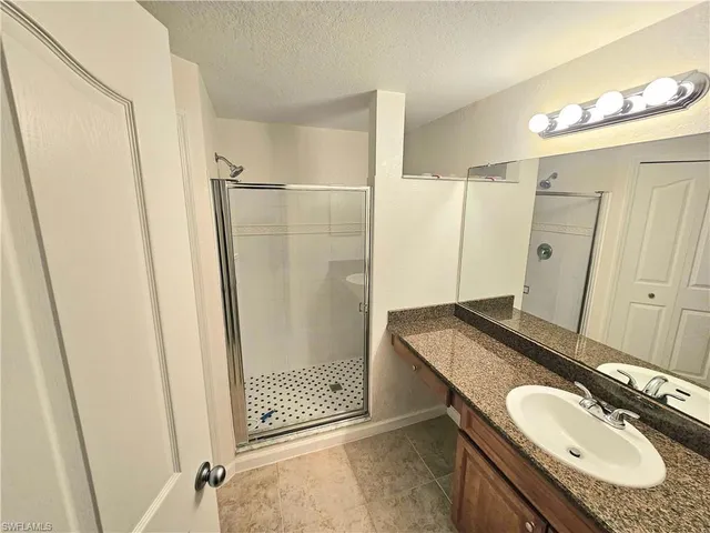 a bathroom with a granite countertop sink a mirror and shower