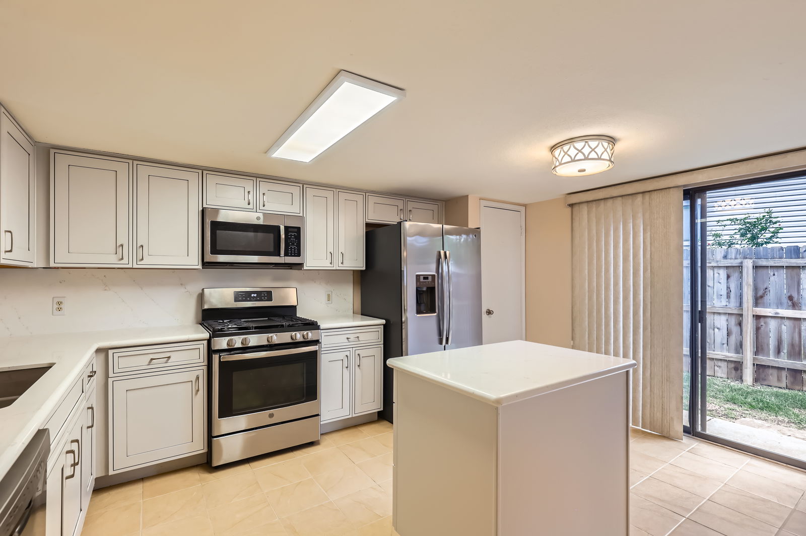 4513 Sidereal Drive Austin, TX 78727 - Photo 12 of 38 Kitchen features grey cabinets with backsplash, quartz countertops, track lighting and tile flooring.