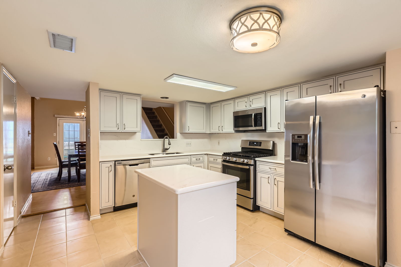 4513 Sidereal Drive Austin, TX 78727 - Photo 13 of 38 Kitchen featuring stainless steel appliances, quartz countertops, a kitchen island, ceramic tile floor, and a decorative ceiling light fixture.