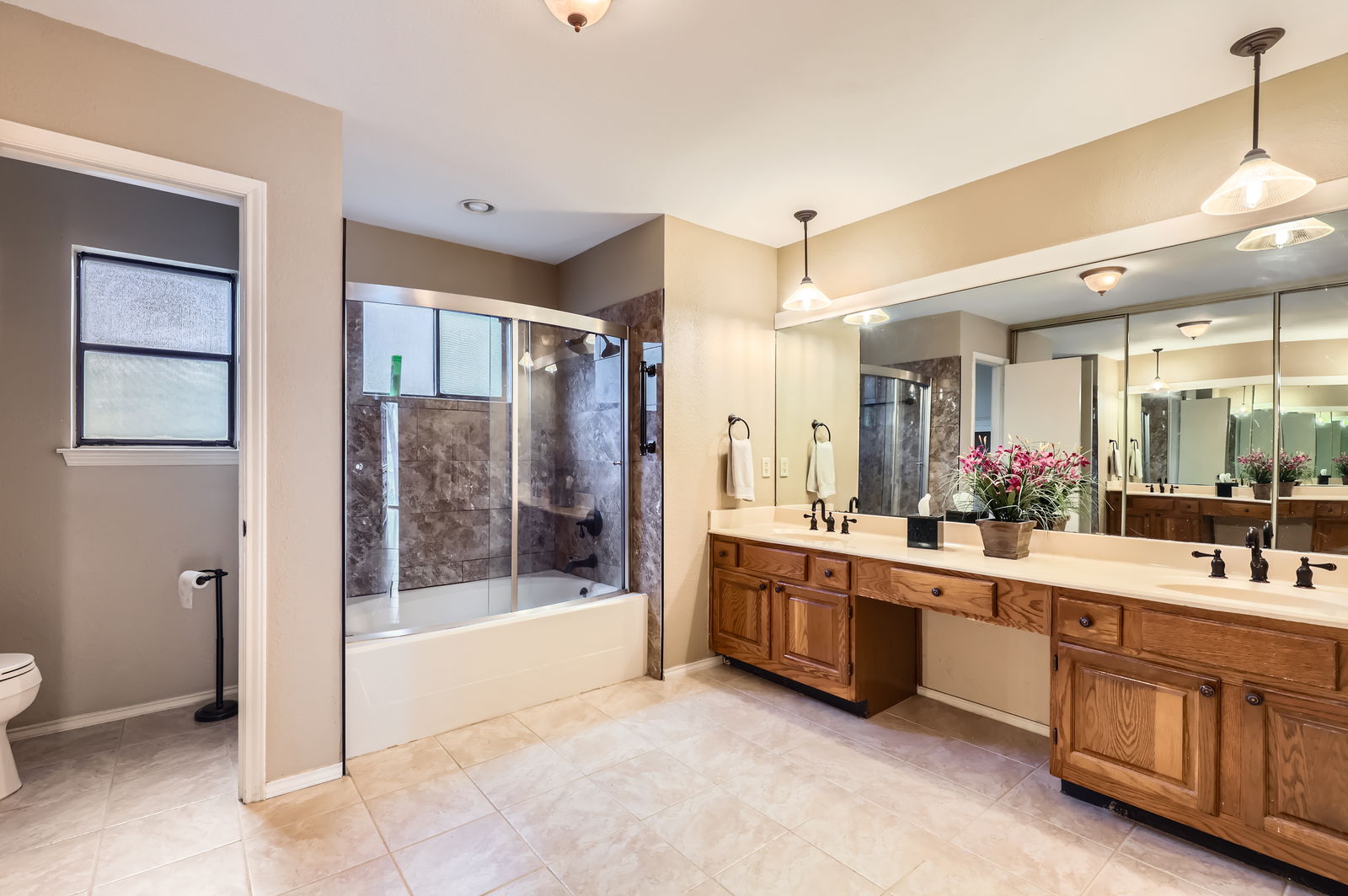 4513 Sidereal Drive Austin, TX 78727 - Photo 20 of 38 Primary bath featuring double vanity, bath / shower combo with glass door and pendant lighting.