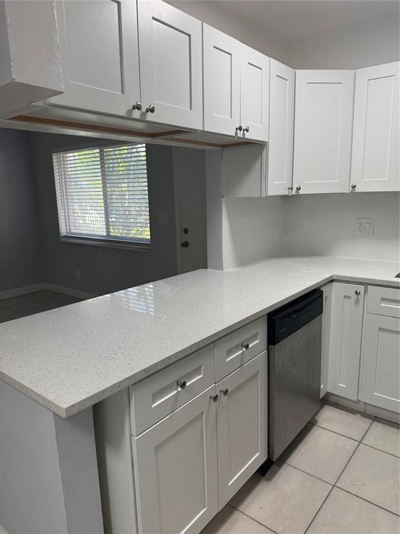 3050 Northeast 5th Terrace, Unit 6 Wilton Manors, FL 33334 - Photo 8 of 22 a kitchen with granite countertop white cabinets and white appliances
