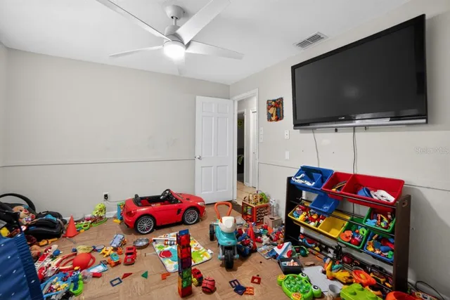 a living room with lots of baby toys and flat screen tv