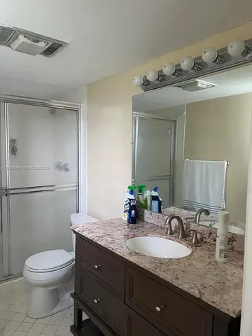 a bathroom with a granite countertop sink a toilet and a mirror