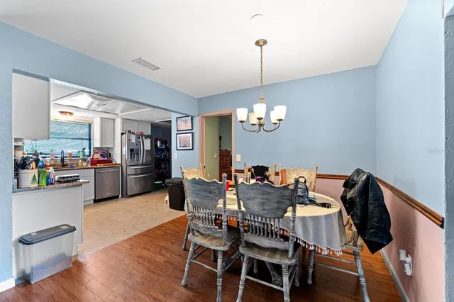a view of a dining room and livingroom with furniture wooden floor a chandelier