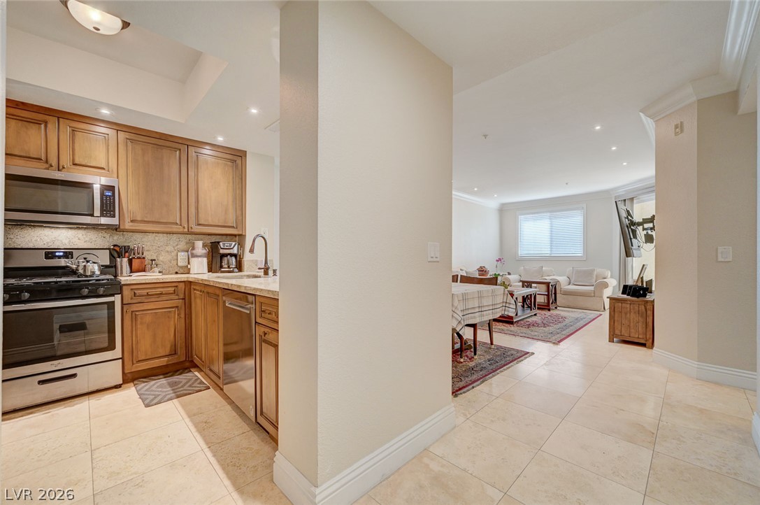 230 East Flamingo Road, Unit 106 Las Vegas, NV 89169 - Photo 3 of 66 A functional kitchen boasts stainless steel appliances, seamlessly flowing into the adjacent dining and living areas.