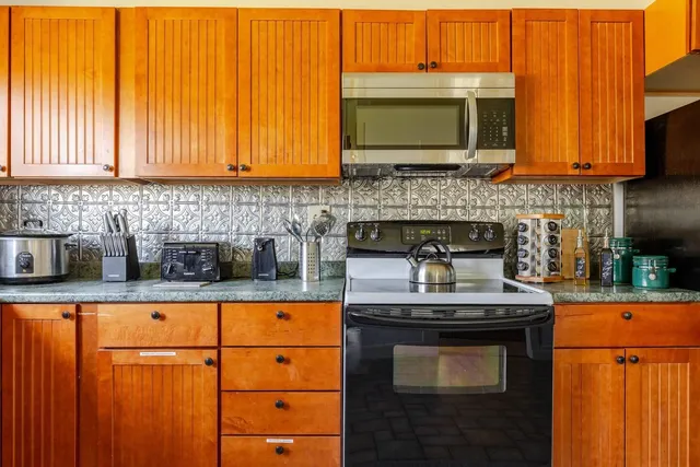 a kitchen with stainless steel appliances a dining table chairs stove refrigerator and cabinets