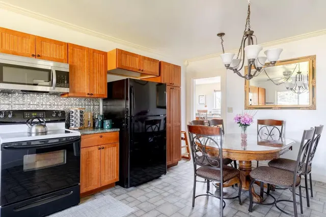 a kitchen with stainless steel appliances granite countertop a refrigerator a stove top oven a dining table and chairs