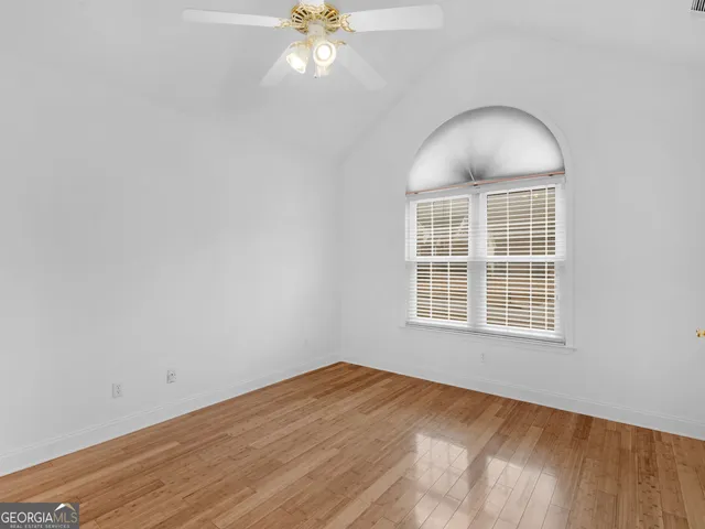 a view of an empty room with window and wooden floor