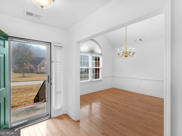 a view of an empty room with window and wooden floor
