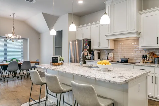 a kitchen with stainless steel appliances granite countertop a sink a stove and a dining table