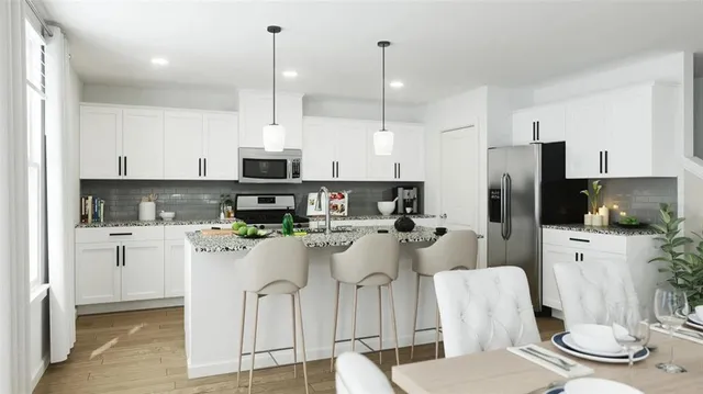 a kitchen with stainless steel appliances kitchen island granite countertop a refrigerator a stove a sink a dining table and chairs with wooden floor