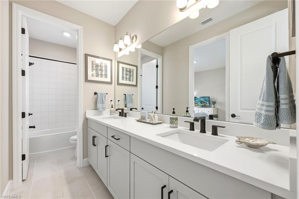 2094 Grove Drive Naples, FL 34120 - Photo 19 of 40 a bathroom with a double vanity sink a mirror a vanity and a bathtub