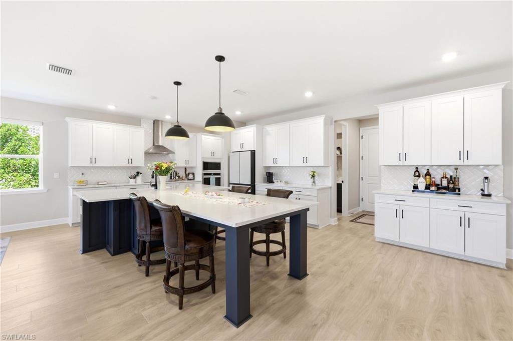2094 Grove Drive Naples, FL 34120 - Photo 5 of 40 a kitchen with stainless steel appliances kitchen island granite countertop a sink a stove a refrigerator and white cabinets with wooden floor