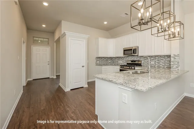 a kitchen with kitchen island granite countertop a sink appliances cabinets and a counter top space