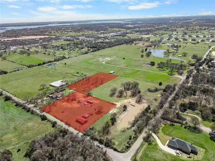 an aerial view of a residential houses with outdoor space and trees
