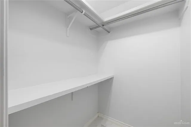 an empty room with chandelier fan and windows