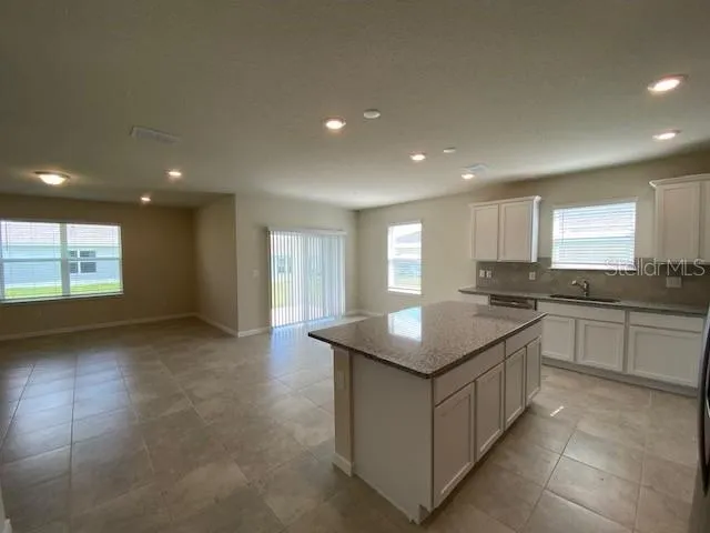 a kitchen with kitchen island granite countertop a stove and a sink