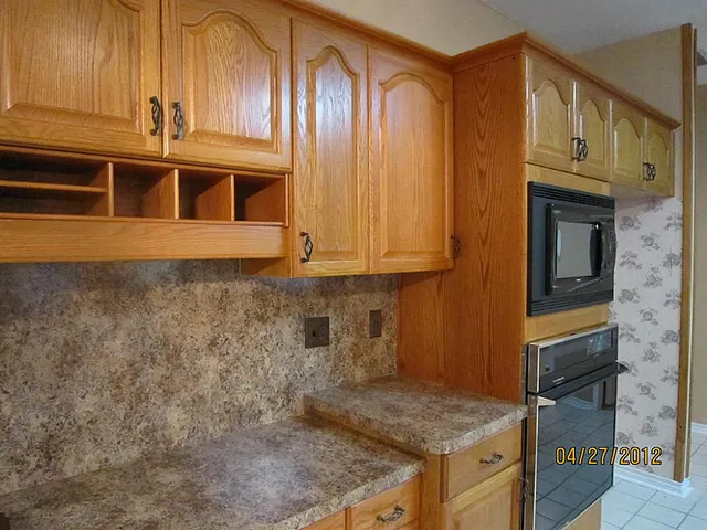 a kitchen with granite countertop a sink cabinets and stainless steel appliances
