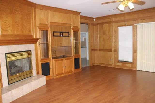 an empty room with wooden floor fireplace and windows