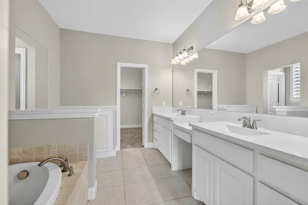 a bathroom with a double vanity sink mirror and bathtub