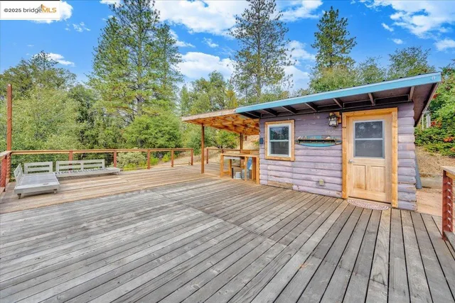 a view of a barn in the backyard with large tree and wooden fence