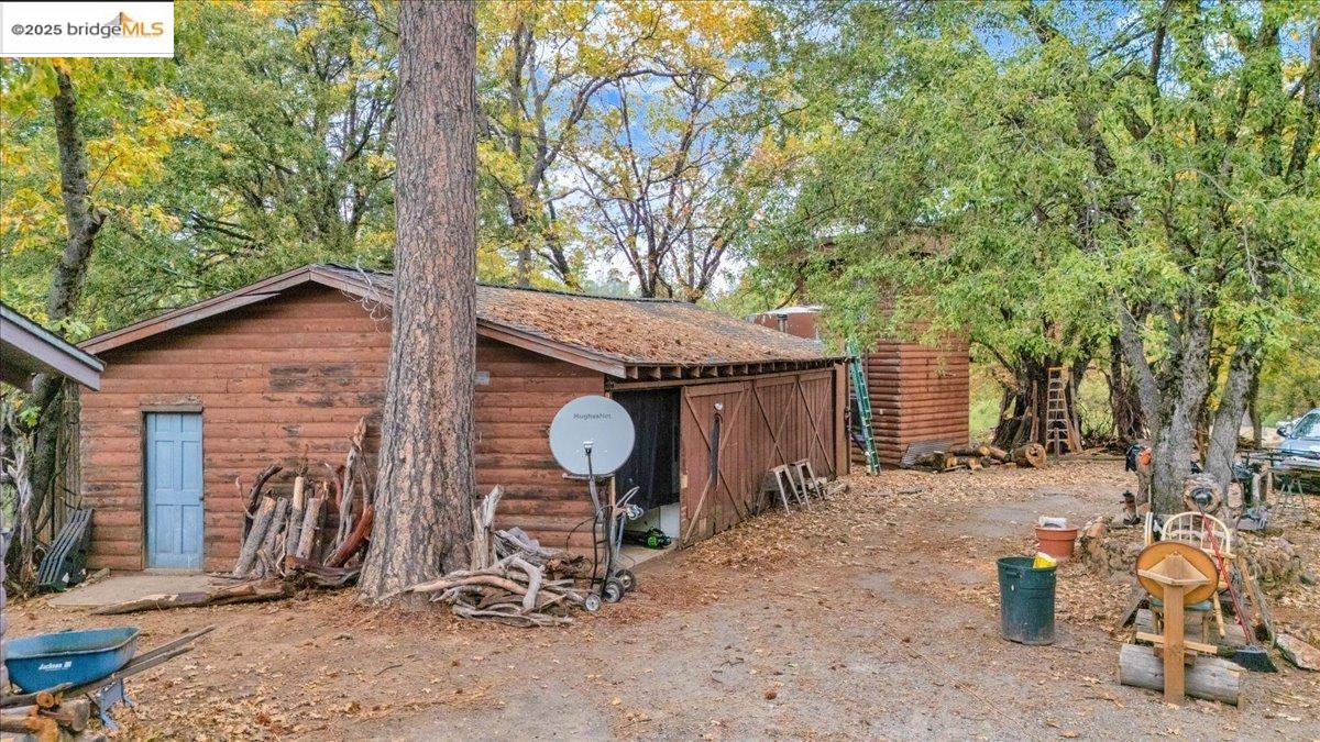 25300 Italian Bar Road Columbia, CA 95310 - Photo 24 of 60 a view of a barn in the backyard with large tree and wooden fence