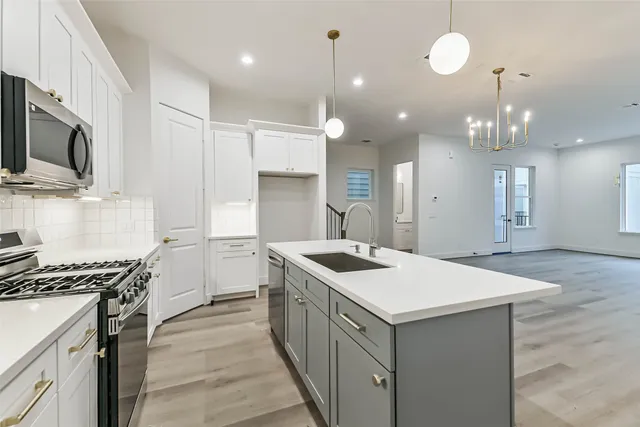 a kitchen that has a sink a microwave oven a stove and a center island